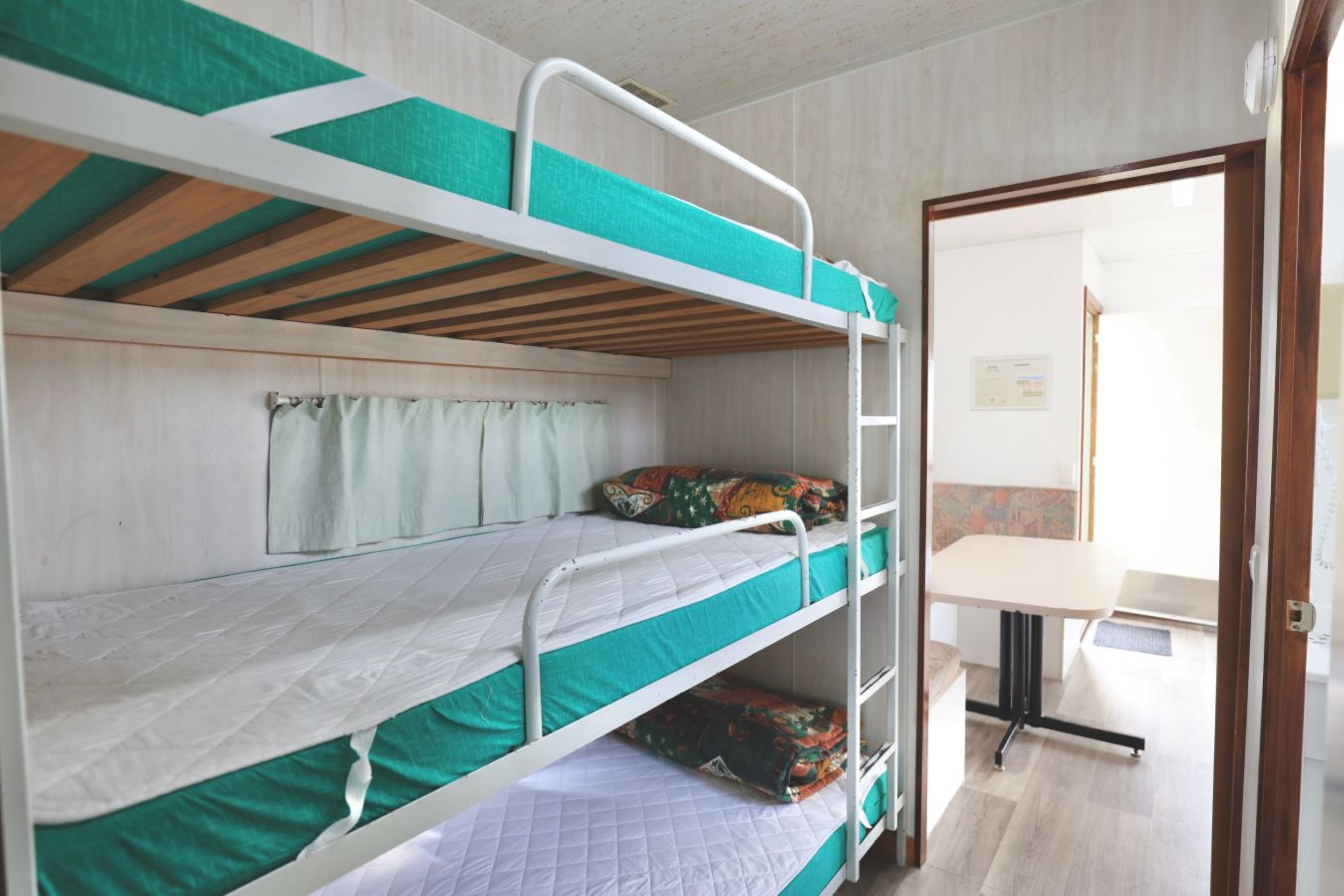 Une chambre avec un lit superposé, un bureau et une fenêtre avec des rideaux.