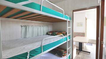 A bunk bed room with a desk and a window with curtains.