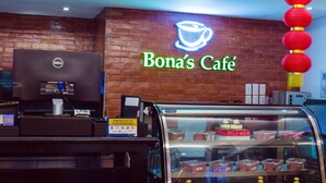 A café with a neon sign, a cash register, and a display case with pastries. - Hotel Fina (Tabaco City)