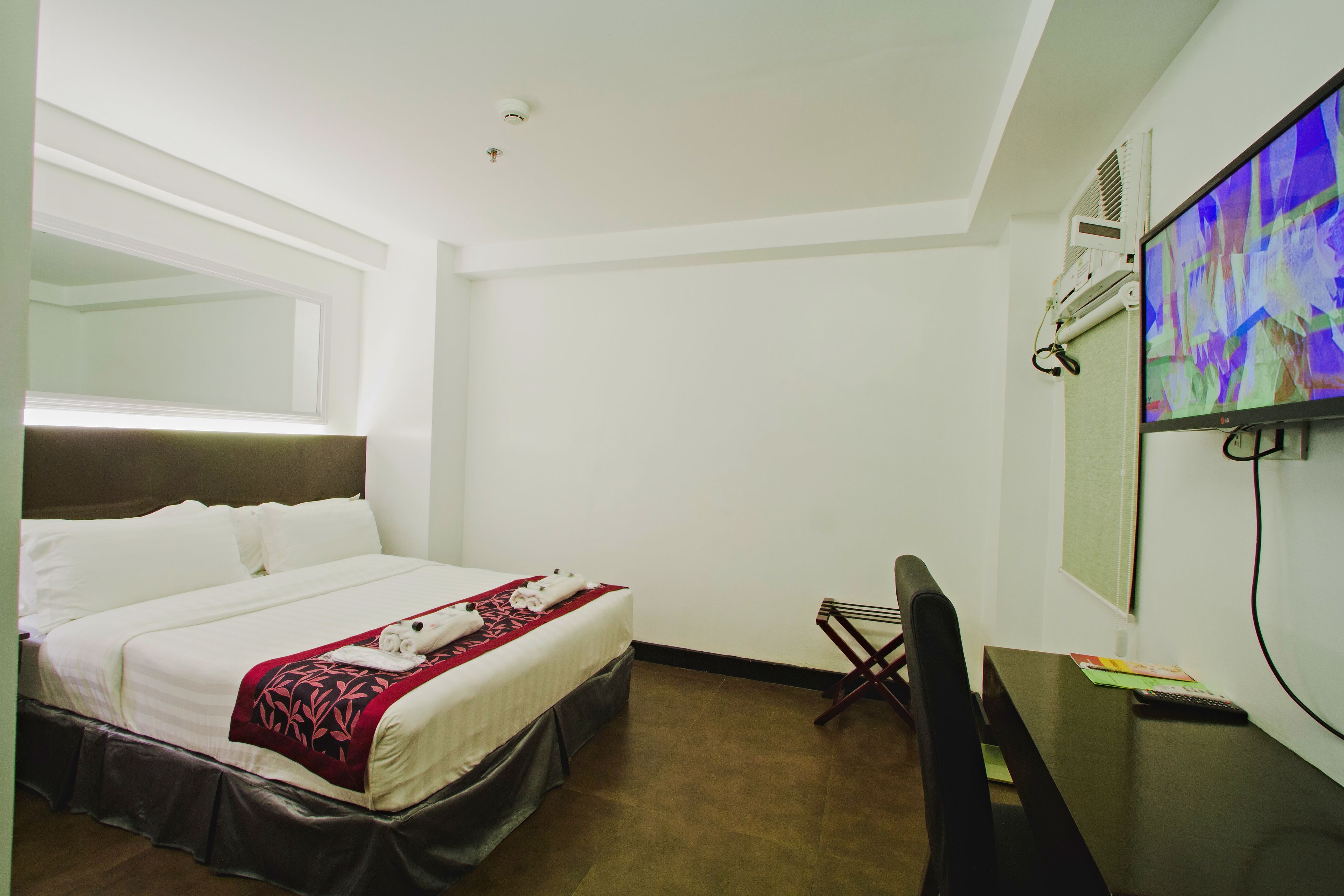 Habitación de hotel con cama, escritorio, silla y televisor.