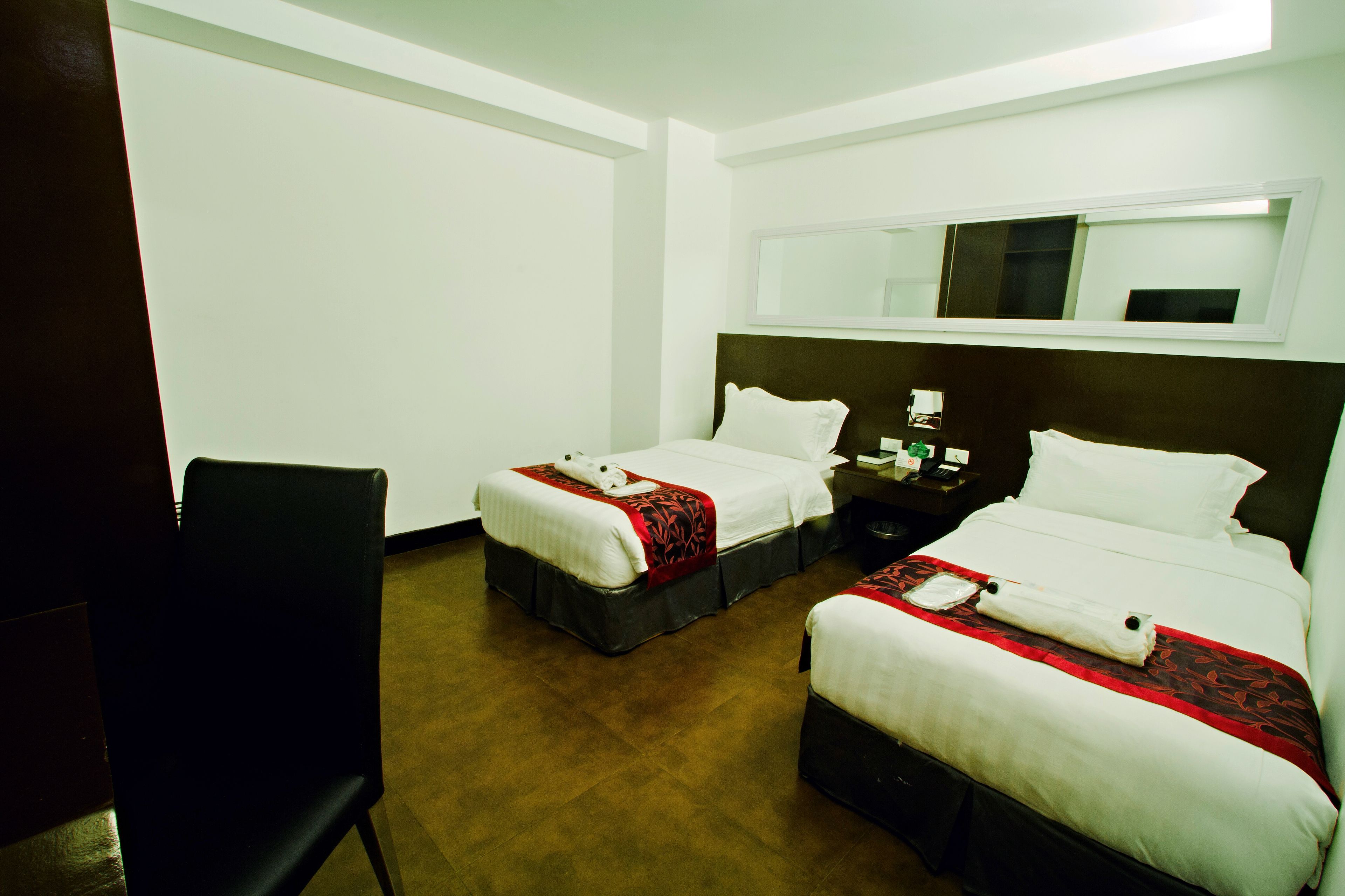 A hotel room with two beds, a desk, and a chair.
