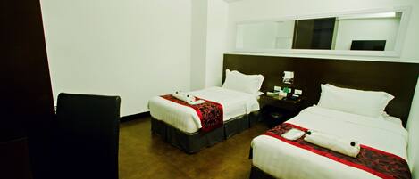 A hotel room with two beds, a desk, and a chair.