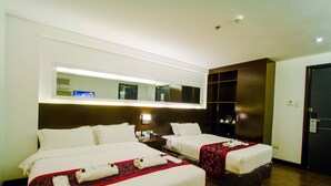 A hotel room with two beds, a large mirror, a nightstand, and a wardrobe. - Hotel Fina (Tabaco City)