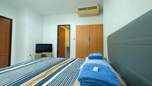 Habitación de hotel con cama, televisión sobre una mesita, armario y equipo de aire acondicionado.
