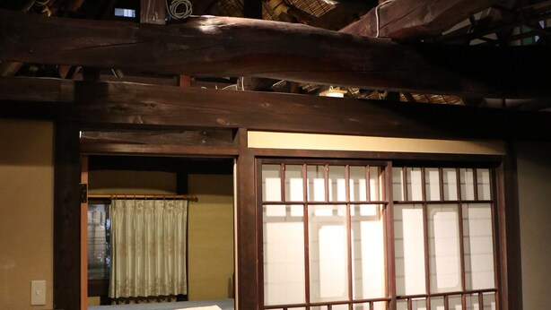 Una habitación japonesa tradicional con suelo de tatami, puertas correderas tipo shoji y techo de paja.