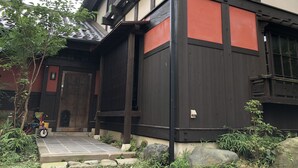 Un edificio japonés tradicional con puerta de madera, un pequeño porche y entrada con tejas.