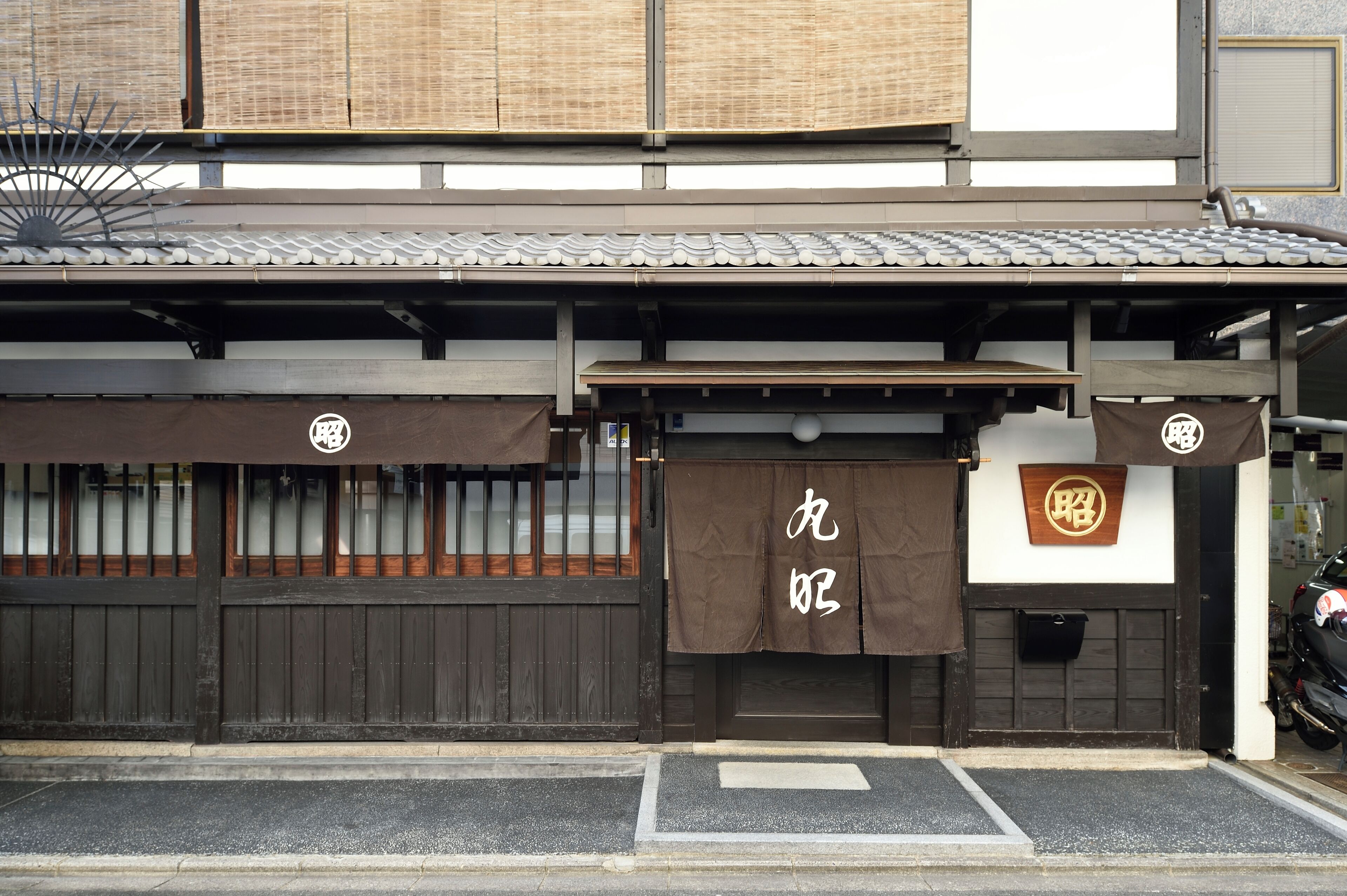 A traditional Japanese building with a wooden facade, a tiled roof, and a sign with Japanese characters.