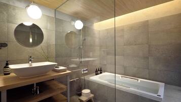 A modern bathroom with a wooden vanity, a large round mirror, a freestanding bathtub, and a glass shower enclosure.