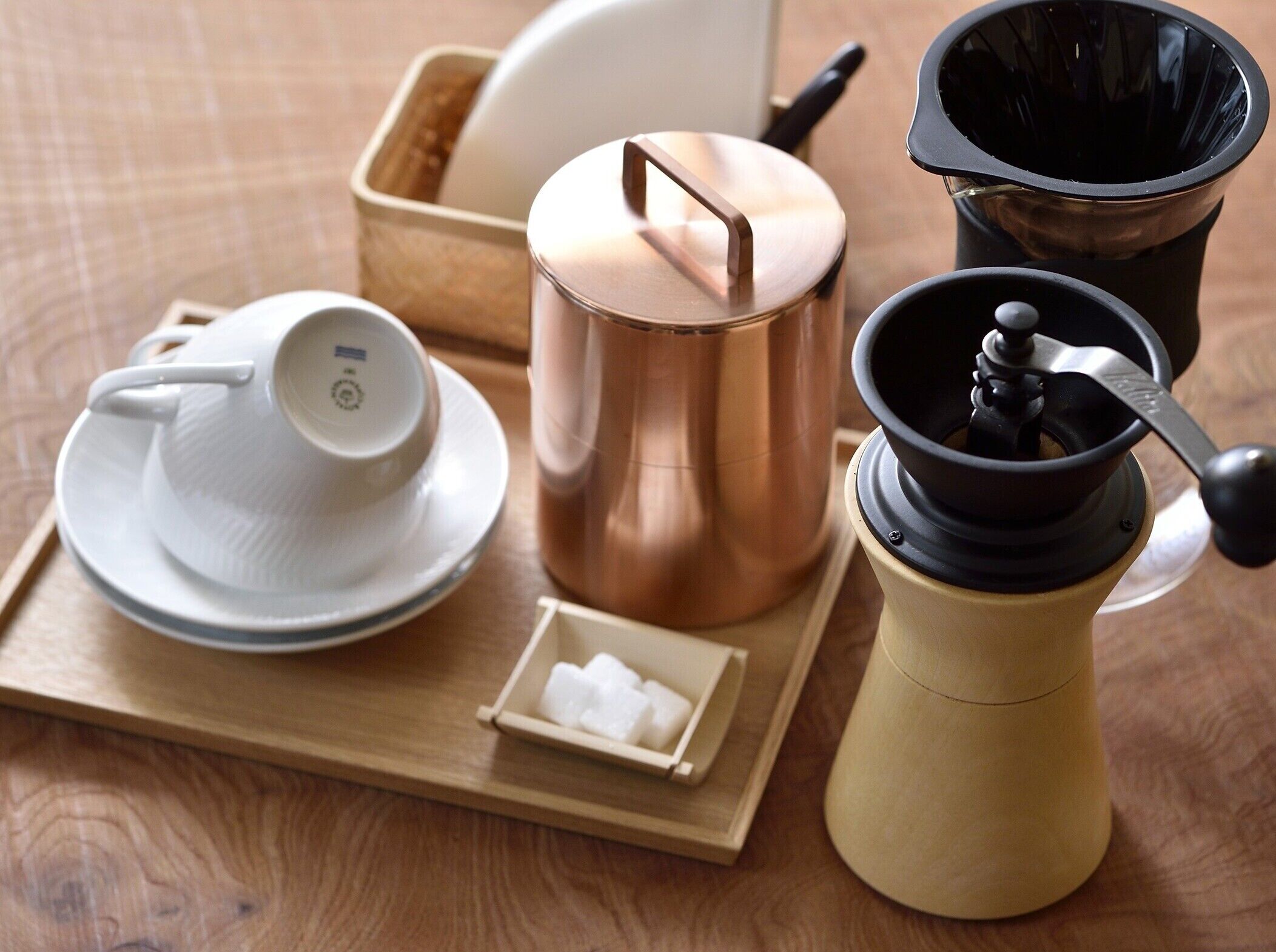 A tray with a teapot, a cup, a sugar container, and a coffee grinder.