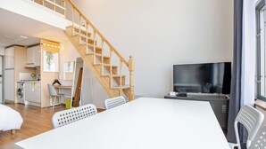 En modern lägenhet med matplats, kök, vardagsrum och en trappa.