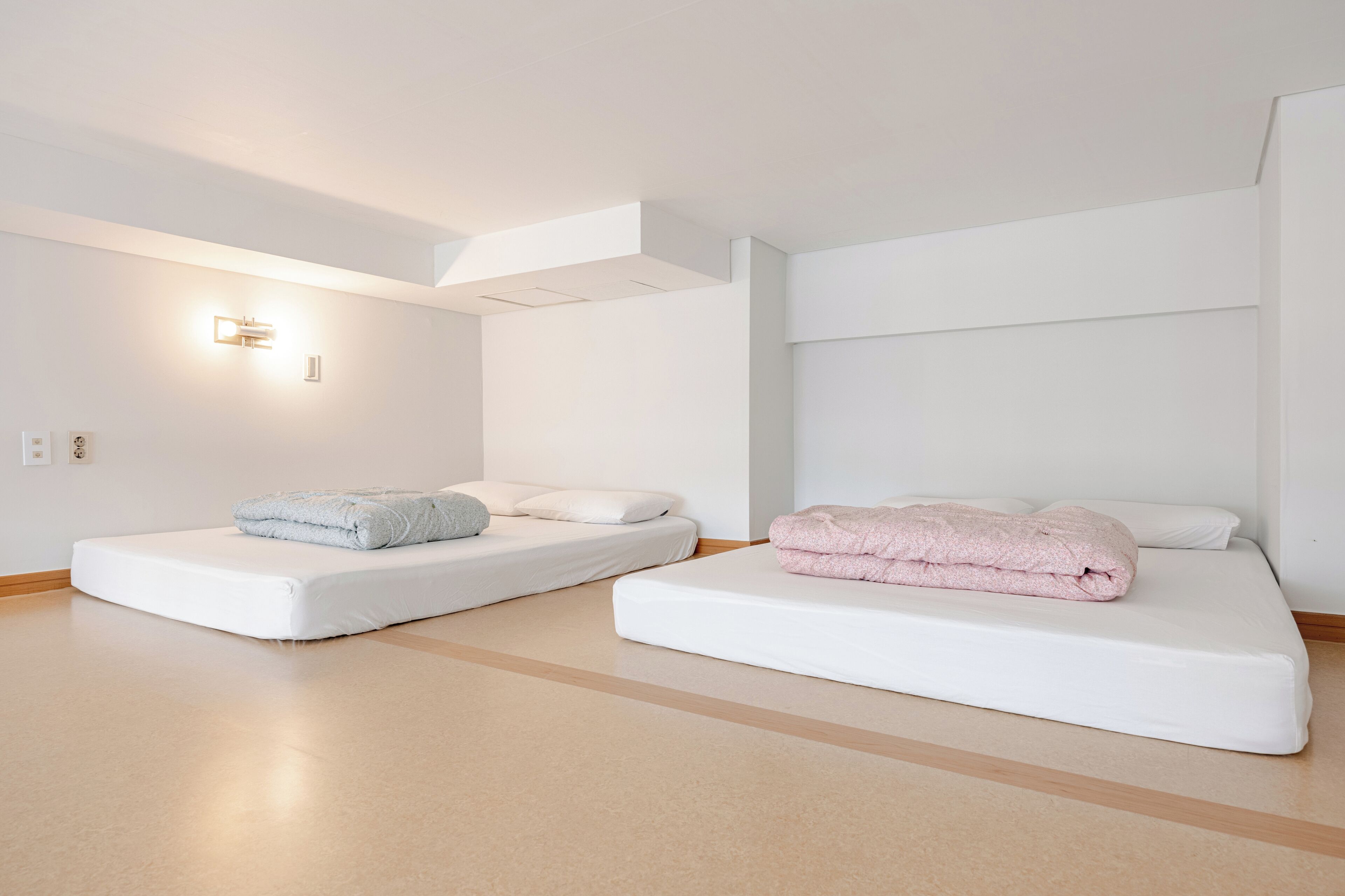 Habitació d'hotel moderna amb dos llits individuals, una finestra gran i un disseny minimalista.