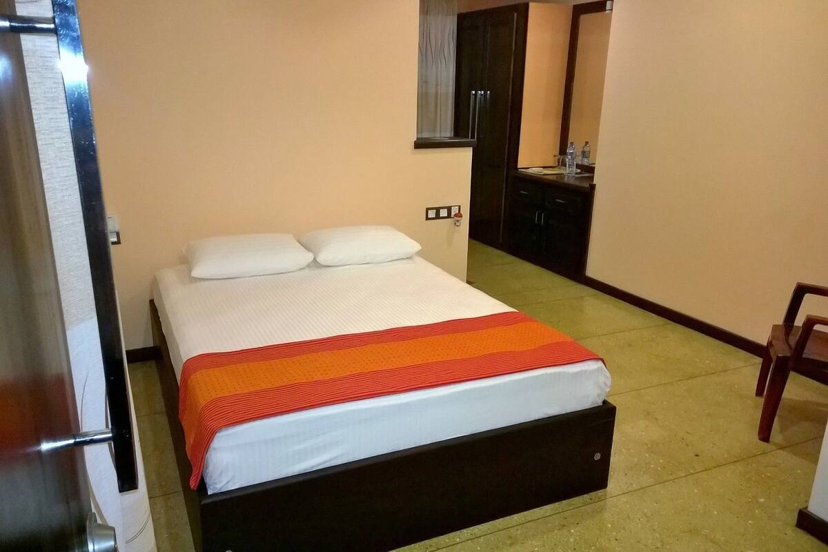 A hotel room with a bed, a small desk, and a chair.