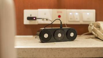 A portable speaker on a countertop with a power strip in the background.