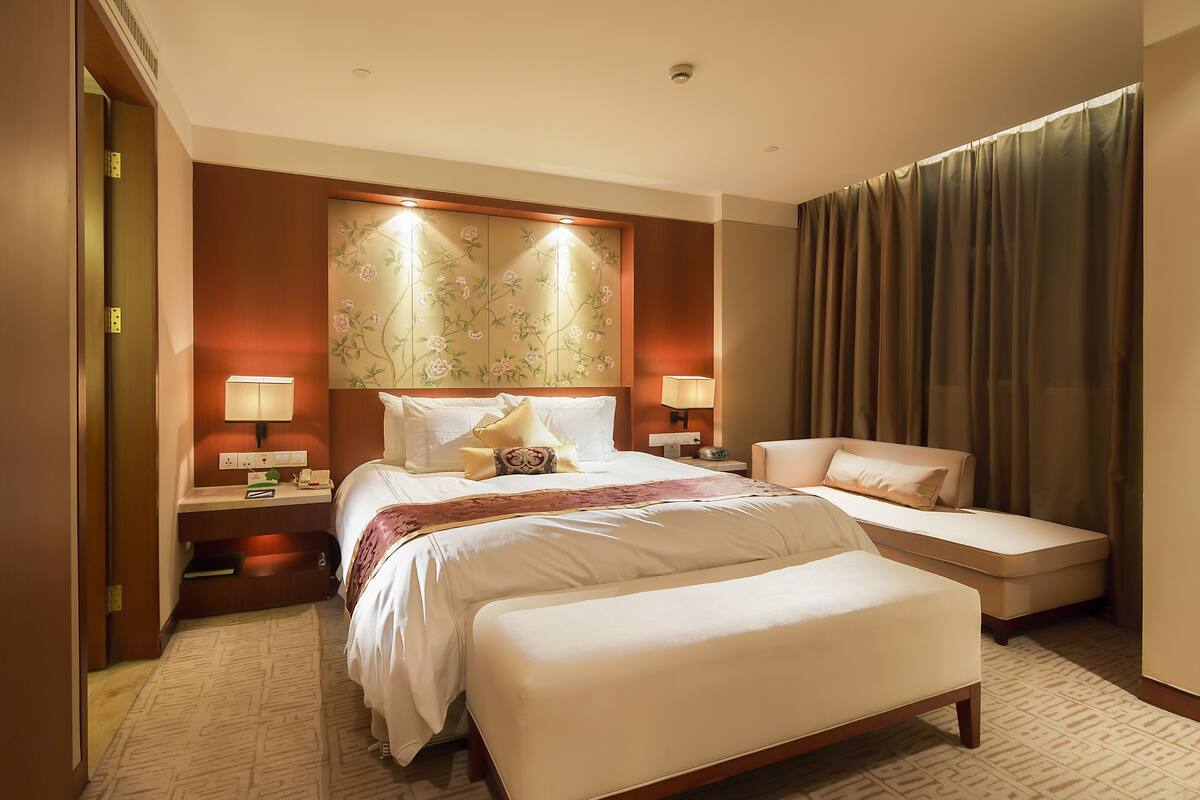 Une chambre d’hôtel avec un grand lit, un lit plus petit, un canapé, un bureau et une table de chevet.