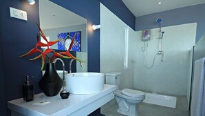A modern bathroom with a white sink, a toilet, and a shower. - Anjali (Koh Samui)