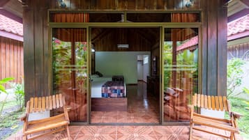 A wooden structure with a glass door leading to a bedroom with a bed and a desk.