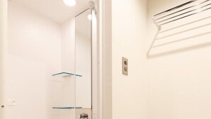 Een badkamer met een douchecabine van glas, een handdoekrek en een wandgemonteerde airconditioning.