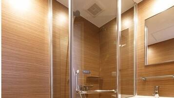 A modern bathroom with a glass-enclosed shower, a white sink, and a mirror above it.