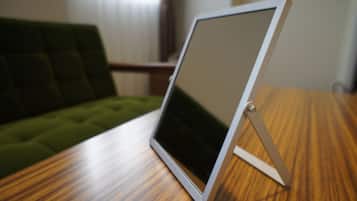 A tablet on a wooden table with a green couch in the background.