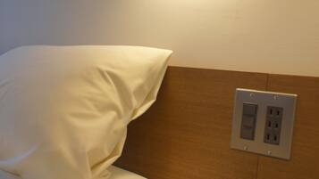 A neatly made bed with white bedding, a wooden headboard, and a wall-mounted clock.