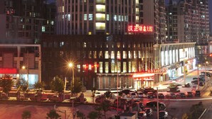 A tall hotel building with illuminated windows and a neon sign. - Roying Hotel (Wuhan)