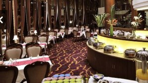 A hotel lobby with a curved reception desk, multiple dining tables, and a patterned carpet. - Roying Hotel (Wuhan)