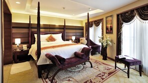 A four-poster bed with a white bedspread and multiple pillows, a nightstand with a lamp, a dark wooden headboard, a large window with curtains, and a decorative rug. - Roying Hotel (Wuhan)