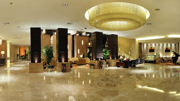 A spacious lobby with a reception desk, seating areas, and a large chandelier. - Roying Hotel (Wuhan)