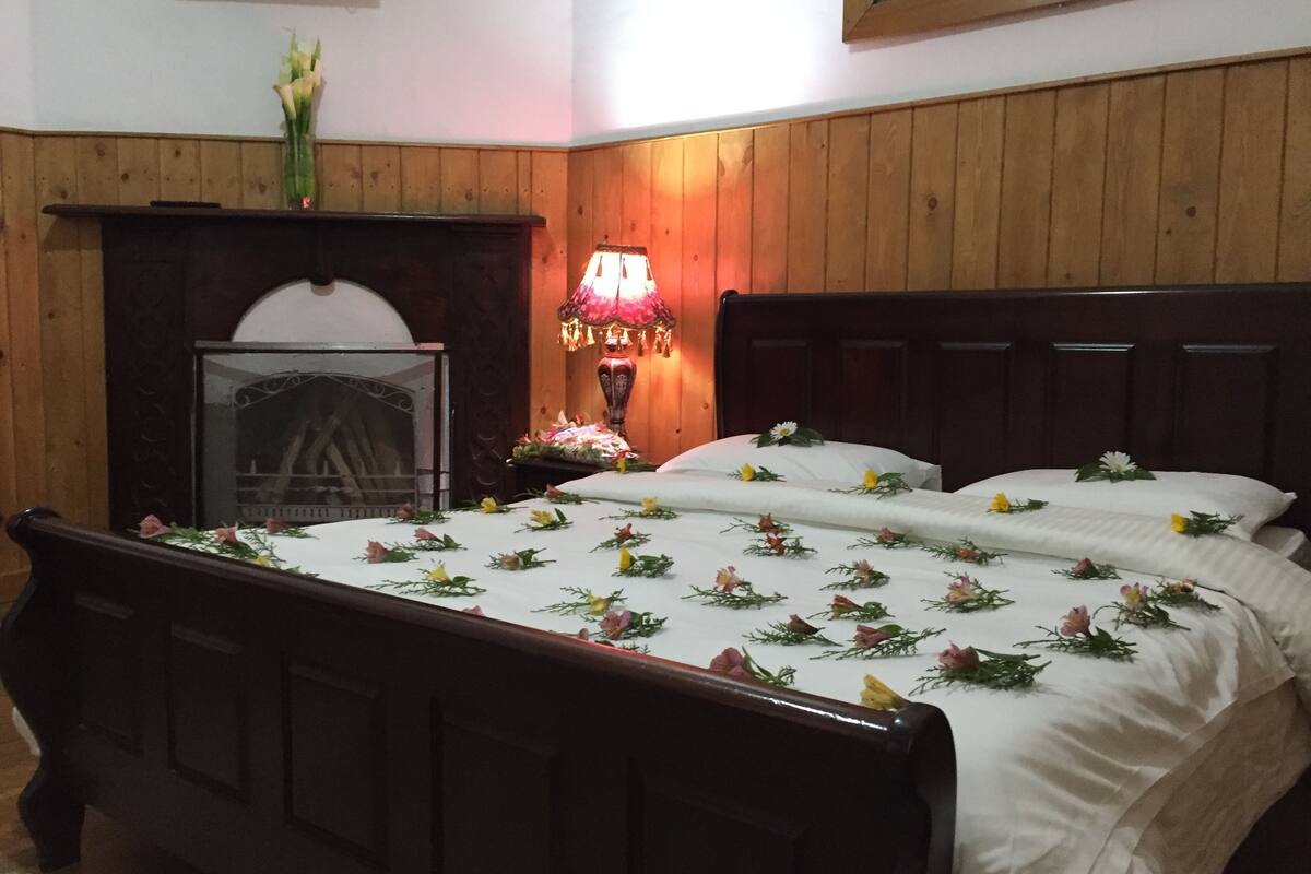 Une chambre à coucher avec une tête de lit en bois, une table de chevet avec une lampe et un lit recouvert d’une literie à motifs floraux.