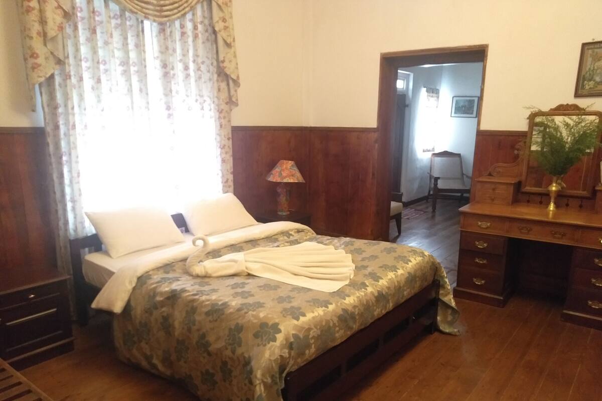 Une chambre avec un lit, une commode en bois et un bureau.