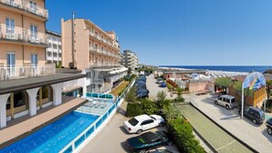 A hotel with a pool, multiple balconies, and a view of the beach. - Dea Hotel (Cervia)