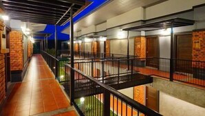 Un pasillo con varias habitaciones, un balcón con barandilla y techo azul.
