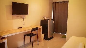 Una pequeña kitchenette con refrigerador, una encimera de madera y una silla.