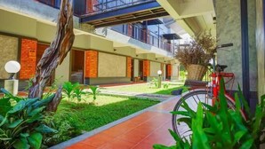 Un edificio moderno con un patio interior, una bicicleta roja y un árbol grande.