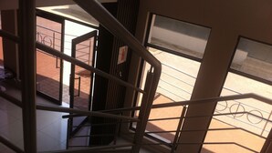 A view from a staircase inside a building, looking out to a brick-paved area with a fire extinguisher mounted on the wall. - Hotel LaBama (Gaborone)