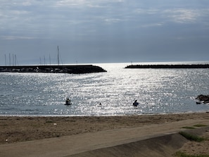 A beach with a sandy shore and calm water reflecting sunlight. - Guesthouse Kazenoie Bonita - Caters to Women (Sennan)