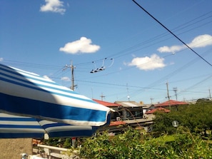 A clear blue sky with power lines and a striped umbrella in the foreground. - Guesthouse Kazenoie Bonita - Caters to Women (Sennan)