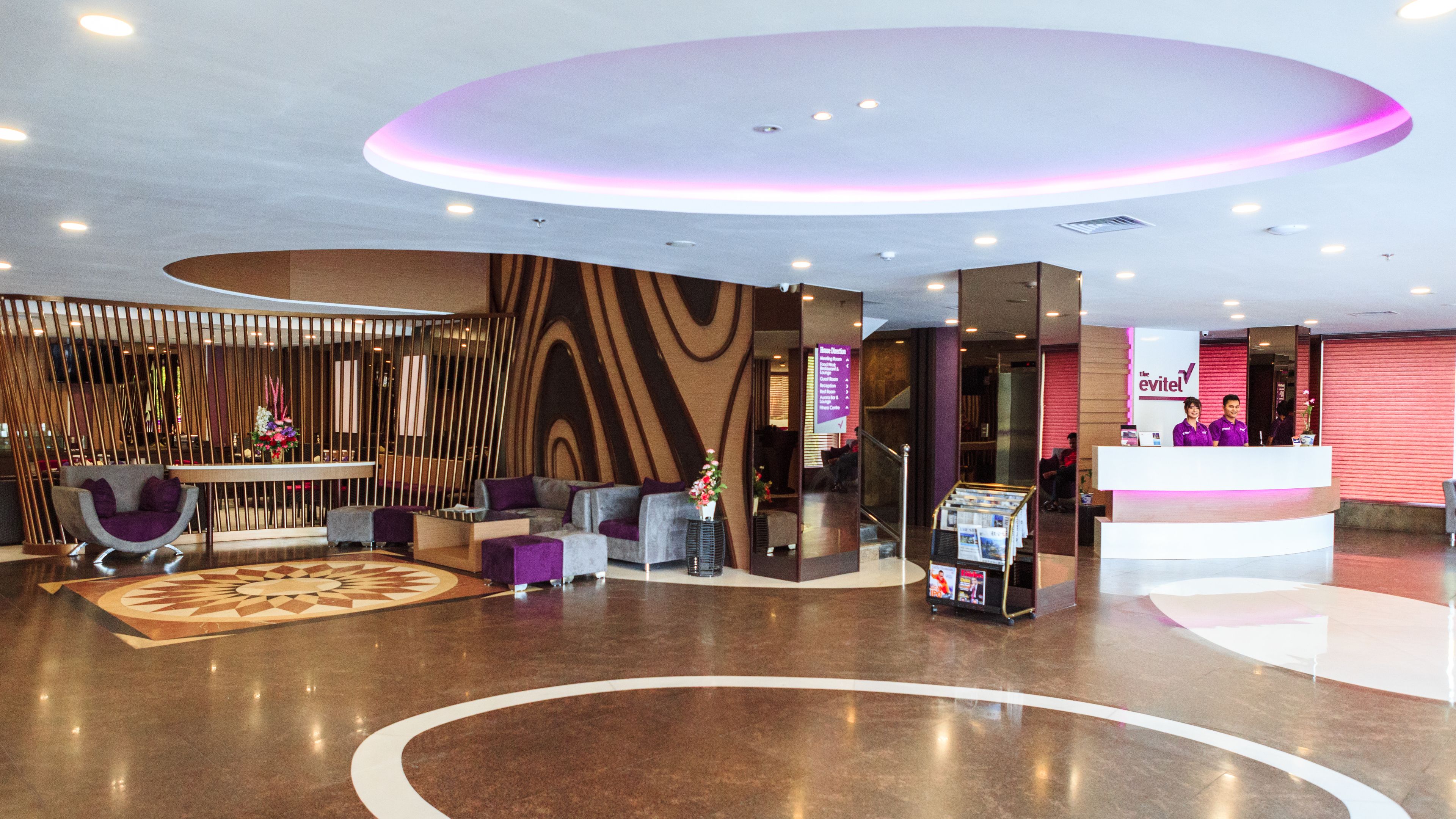 Eine moderne Hotelhalle mit Empfangsbereich, einer Sitzecke und einer Dekowand.