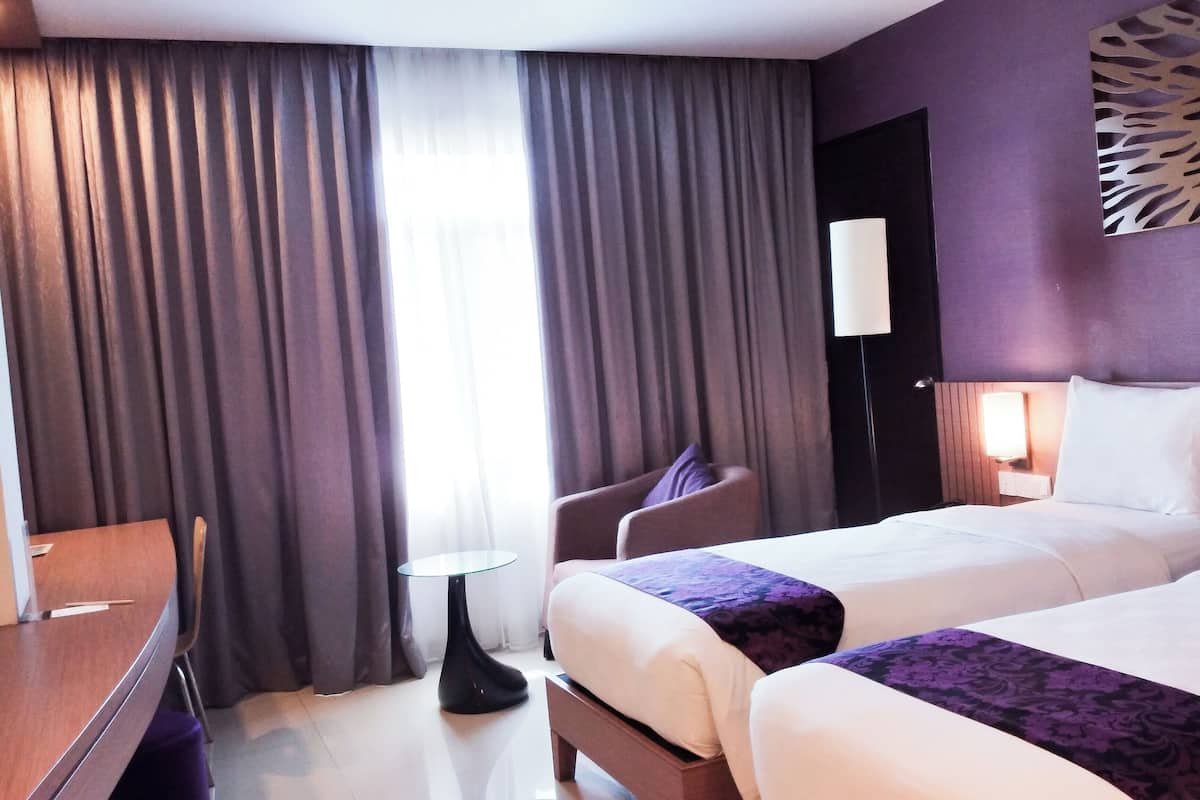 Een hotelkamer met twee bedden, een bureau, een stoel en een klein tafeltje.