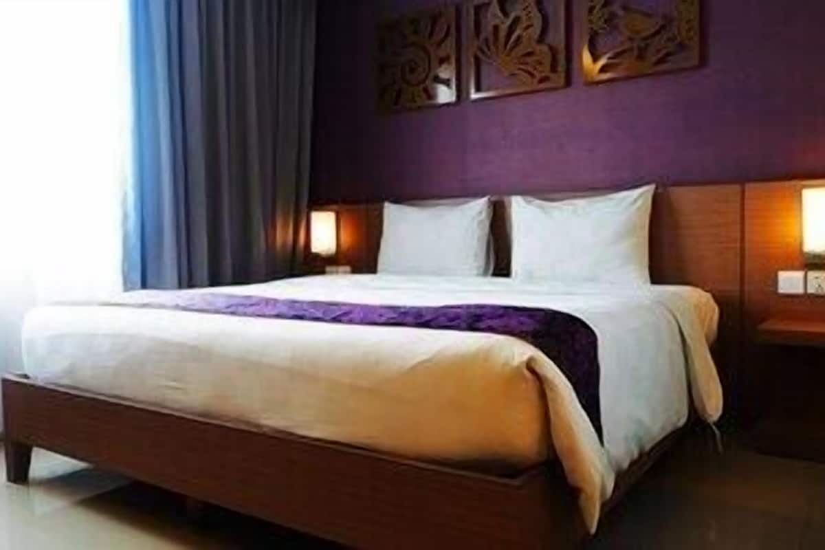 Een hotelkamer met een bed, nachtkastje en decoratie aan de muur.