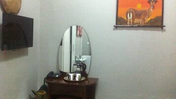 Una habitación con un escritorio de madera, un espejo, un teléfono y un cuadro en la pared.
