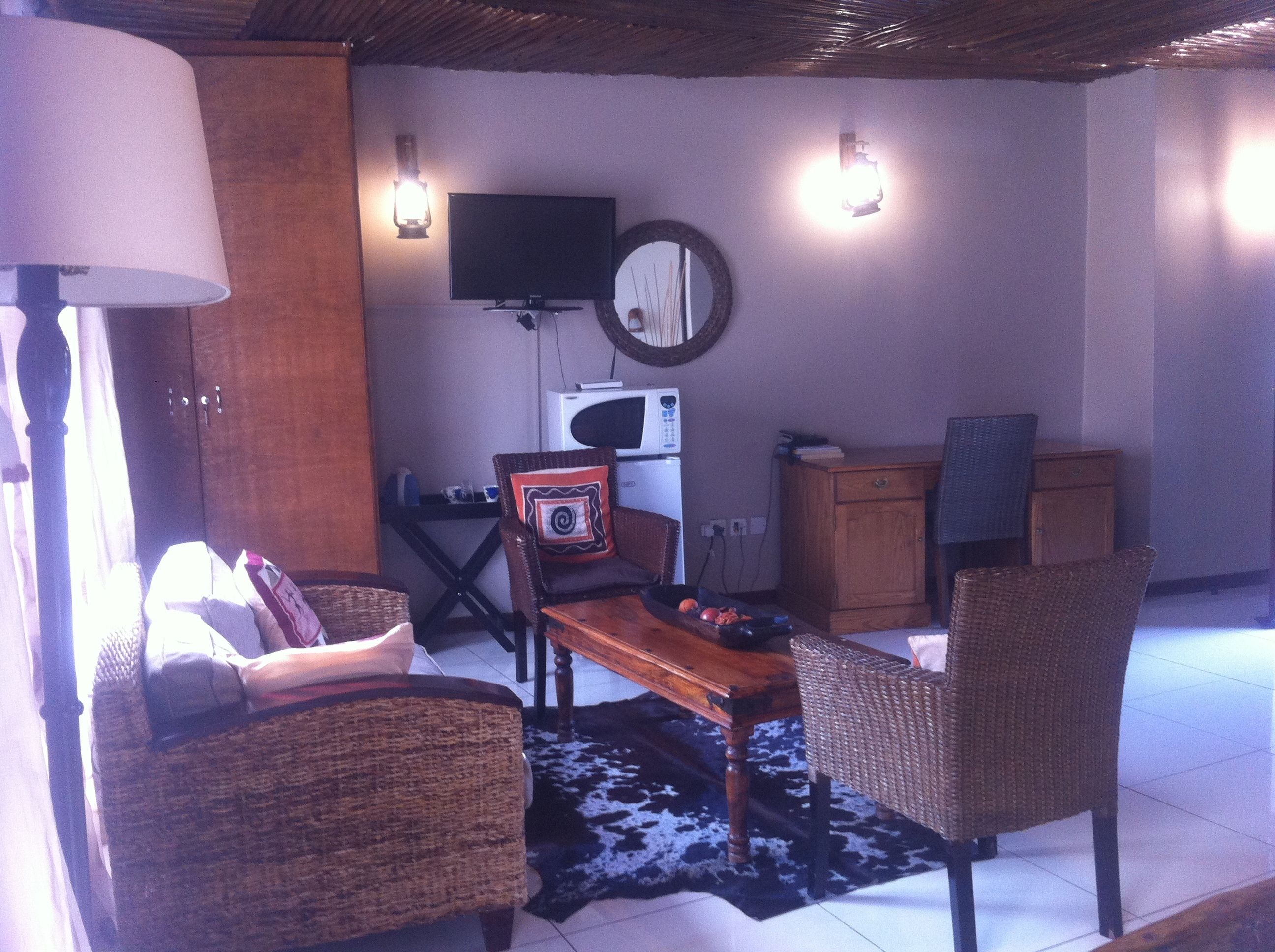 A living room with wicker furniture, a wooden table, a television, and a microwave.