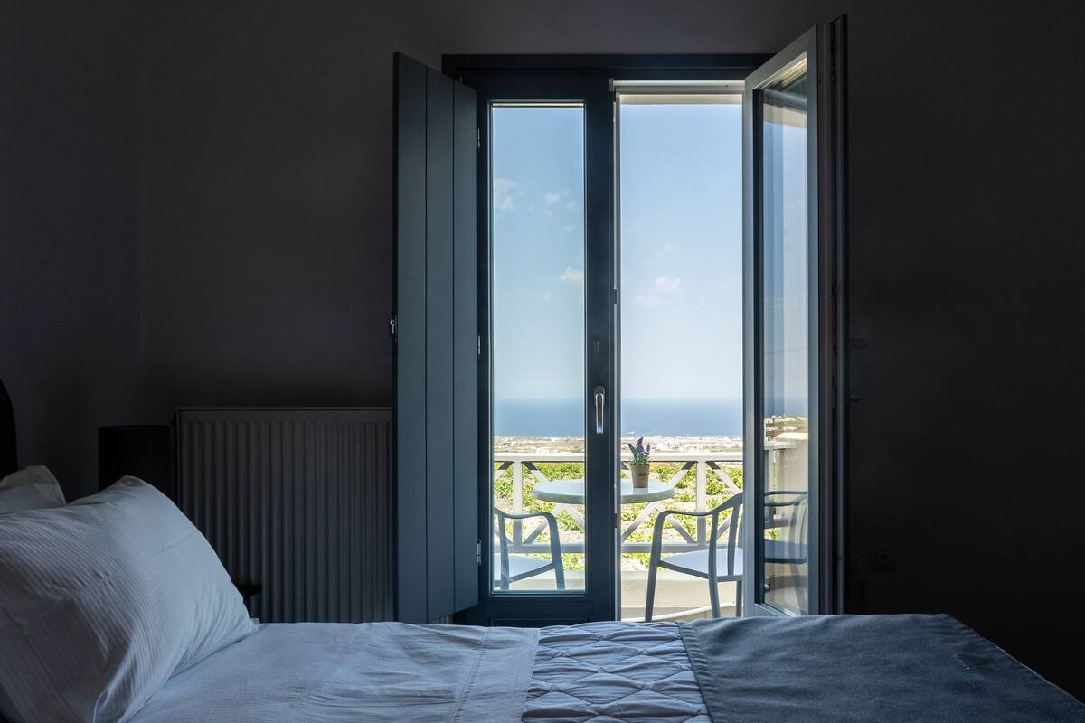 A bedroom with a bed, a radiator, and a sliding glass door leading to an outdoor area with a table and chairs.