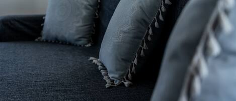 A dark blue sofa with two light blue pillows, one with a tassel detail.