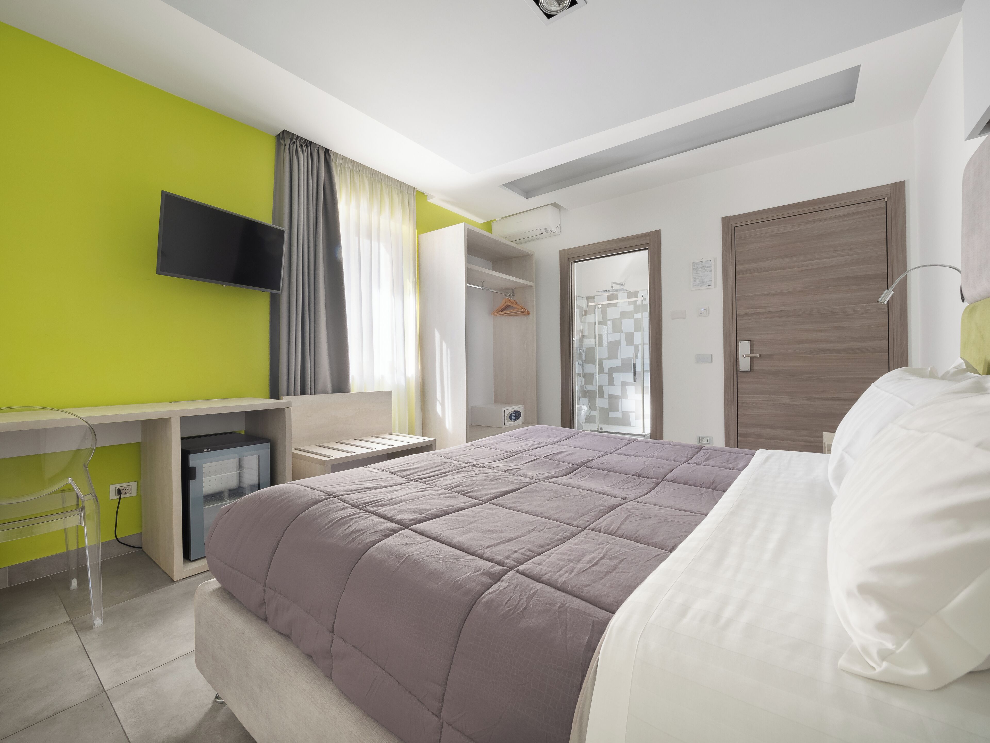 Une chambre à coucher moderne avec un lit, un bureau et un téléviseur.