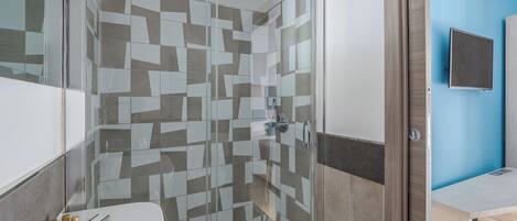 Ein modernes Badezimmer mit Duschkabine aus Glas, einem weißen Waschbecken und einer blauen Akzentwand.