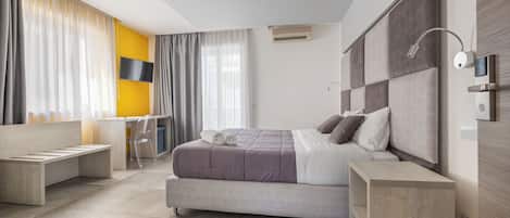 A modern bedroom with a large bed, bedside tables, a desk, and a chair.