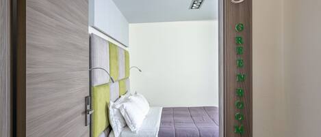 Un dormitorio con cama, mesita de noche y una puerta con número.