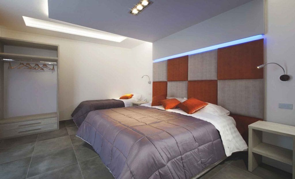 A modern bedroom with a bed, bedside tables, and a built-in wardrobe.