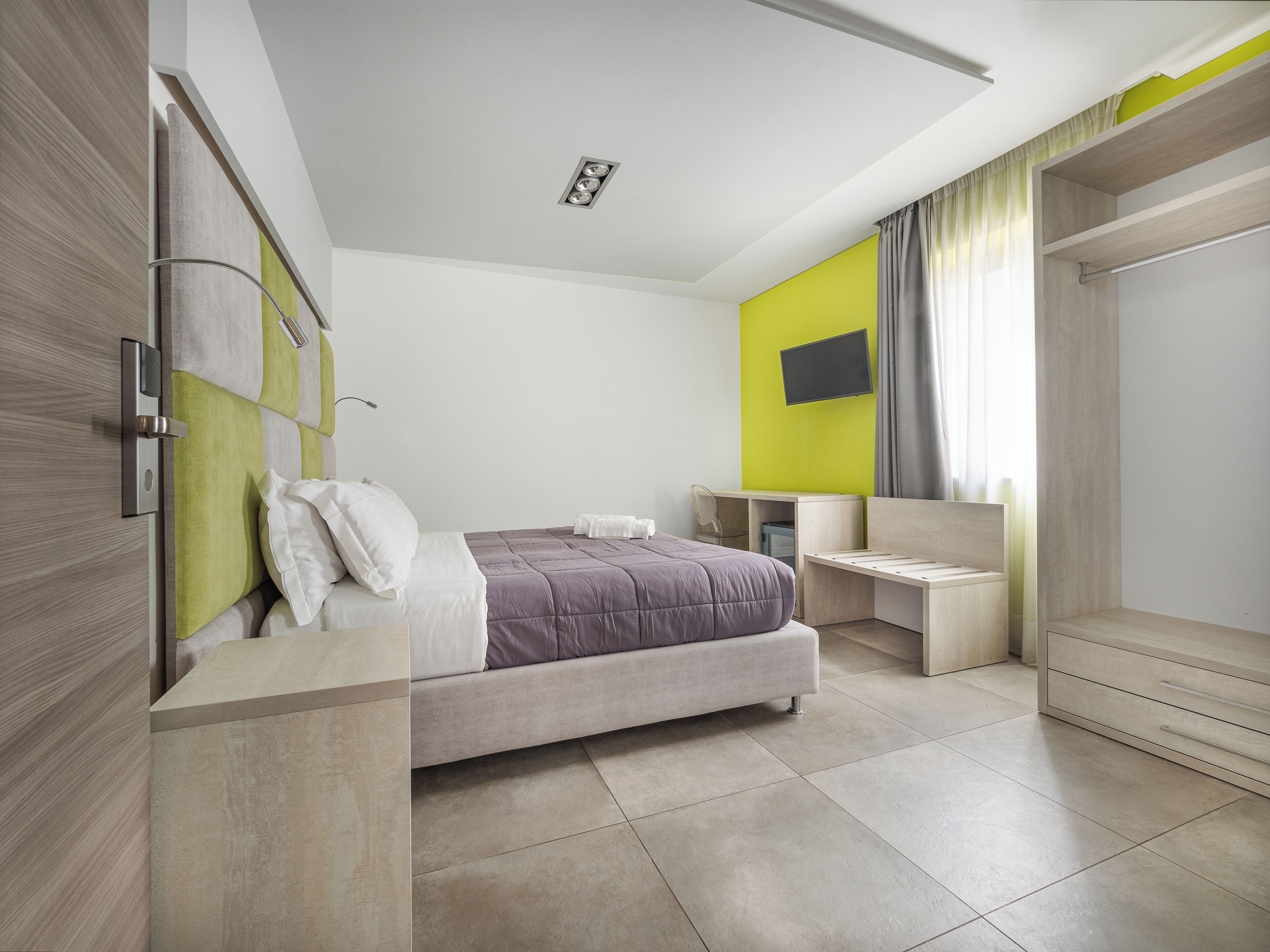 A modern bedroom with a bed, bedside tables, a desk, and a wardrobe.
